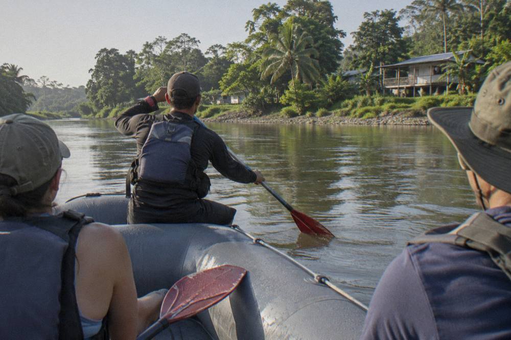 A guide demonstrating paddle strokes to a raft crew on a calm stretch of river before the rapids